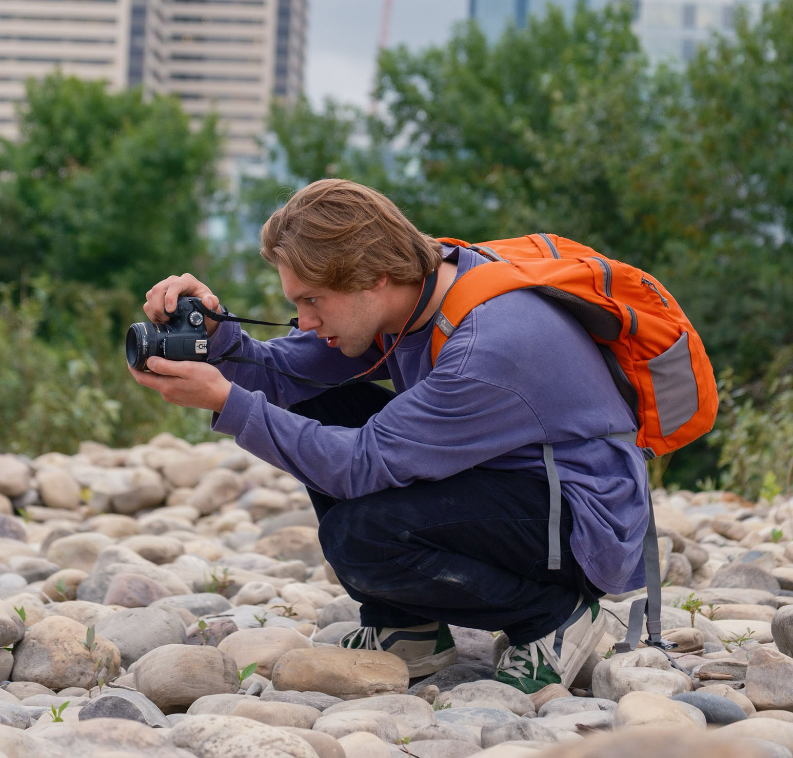 Photo of Aiden Johner kneeling using a camera.